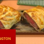 # Beef Wellington: Uma Delicada Obra-Prima Culinária ## Introdução O **Beef Wellington** é um dos pratos mais icônicos e refinados da gastronomia internacional. Com uma rica história e uma apresentação impressionante, essa receita consiste em um suculento filé mignon revestido com uma camada de patê, frequentemente patê de foie gras, e uma duxelles de cogumelos, tudo envolvido em uma massa folhada dourada e crocante. A combinação de sabores e texturas faz do Beef Wellington uma escolha popular para ocasiões especiais e celebrações. Neste artigo, exploraremos a história do Beef Wellington, discutiremos seus ingredientes principais e apresentaremos uma receita detalhada para você preparar esse clássico em sua própria cozinha. Além disso, abordaremos algumas dicas para garantir o sucesso do prato e variações que você pode experimentar. Ao final, incluiremos uma tabela nutricional e uma chamada para que você compartilhe essa deliciosa receita com seus amigos e familiares. ## História e Origem do Beef Wellington O **Beef Wellington** tem uma origem envolta em mistério e debate. Uma teoria popular sugere que o prato foi nomeado em homenagem ao Duque de Wellington, Arthur Wellesley, que derrotou Napoleão Bonaparte na Batalha de Waterloo em 1815. Outra versão propõe que o nome deriva de uma cidade na Nova Zelândia. Apesar dessas teorias, não há evidências concretas que provem sua origem. Independentemente de sua origem, o Beef Wellington ganhou fama mundial e se tornou um símbolo de sofisticação e culinária de alta qualidade. O prato é especialmente popular no Reino Unido e nos Estados Unidos, onde é frequentemente servido em restaurantes finos e em ocasiões especiais. ## Ingredientes Principais Os ingredientes de qualidade são fundamentais para o sucesso do **Beef Wellington**. Aqui estão os principais componentes necessários para preparar essa iguaria: ### Ingredientes - **Filé mignon**: 1 peça de aproximadamente 1 kg (de boa qualidade) - **Cogumelos**: 250g de cogumelos frescos (de boa qualidade), finamente picados - **Patê de foie gras** ou patê de fígado de galinha: 100g (opcional) - **Presunto de Parma**: 8 fatias finas - **Massa folhada**: 1 folha grande, descongelada se necessário - **Mostarda Dijon**: 2 colheres de sopa - **Gemas de ovo**: 1, batida para pincelar - **Azeite de oliva**: 2 colheres de sopa (pode ser óleo vegetal também) - **Cebola**: 1 pequena, bem picada - **Alho**: 2 dentes, bem picados - **Tomilho fresco**: 1 colher de chá - **Sal e pimenta**: A gosto ## Receita de Beef Wellington ### Preparação 1. **Preparação dos Ingredientes**: - Pré-aqueça o forno a 200°C. Tempere o filé mignon com sal e pimenta. Aqueça uma frigideira grande com azeite de oliva (ou óleo vegetal) e sele o filé por todos os lados, até dourar. Retire do fogo e pincele a carne com a mostarda Dijon. Deixe esfriar. 2. **Duxelles de Cogumelos**: - Na mesma frigideira, adicione um pouco mais de azeite e refogue a cebola e o alho (bem picados) até ficarem translúcidos. Adicione os cogumelos picados e o tomilho. Cozinhe em fogo médio até que a água dos cogumelos evapore completamente e a mistura esteja seca. Tempere com sal e pimenta. Deixe esfriar. 3. **Montagem**: - Sobre uma superfície plana, estenda um filme plástico. Coloque as fatias de presunto de Parma sobre o filme, formando uma camada. Espalhe a duxelles de cogumelos sobre o presunto. Coloque o filé mignon no centro e, com a ajuda do filme plástico, enrole tudo firmemente, formando um pacote. Leve à geladeira por 15 minutos para firmar. 4. **Envolvendo com Massa Folhada**: - Abra a massa folhada em uma superfície enfarinhada. Retire o pacote de carne da geladeira e desembrulhe. Coloque a carne sobre a massa folhada e enrole, selando as bordas com gemas de ovo batidas. Certifique-se de que a massa esteja bem fechada. Pincele toda a superfície com mais gema de ovo para obter uma cor dourada ao assar. 5. **Assamento**: - Coloque o Beef Wellington em uma assadeira e leve ao forno pré-aquecido. Asse por aproximadamente 25-30 minutos para um filé ao ponto, ou até que a massa folhada esteja dourada e crocante. Deixe descansar por 10 minutos antes de cortar. ### Rendimento Esta receita de **Beef Wellington** serve aproximadamente 6 pessoas. ### Tempo de Preparo - **Tempo de preparação:** 30 minutos - **Tempo de cozimento:** 30 minutos - **Tempo total:** 1 hora ## Dicas para o Sucesso do Beef Wellington 1. **Escolha do Filé**: Utilize um filé mignon de alta qualidade para garantir maciez e sabor. 2. **Selagem Perfeita**: Sele bem a carne para evitar que os sucos escorram durante o cozimento. 3. **Massa Folhada**: Certifique-se de que a massa folhada esteja bem fechada para evitar vazamentos de suco durante o cozimento. 4. **Tempo de Descanso**: Deixe o Beef Wellington descansar antes de cortar para que os sucos se redistribuam pela carne. ## Variações do Beef Wellington Embora a receita tradicional use filé mignon, existem várias variações para explorar: 1. **Beef Wellington de Salmão**: Substitui a carne por salmão, proporcionando uma opção mais leve. 2. **Vegetariano**: Use cogumelos Portobello ou outros vegetais como base, substituindo o filé mignon. 3. **Mini Beef Wellington**: Faça porções individuais usando pequenos pedaços de filé. ## Acompanhamentos para Beef Wellington O **Beef Wellington** é geralmente servido com acompanhamentos que complementam seu sabor rico e complexo. Algumas sugestões incluem: - **Purê de Batatas**: Cremoso e suave, combina perfeitamente com a carne. - **Legumes Salteados**: Como aspargos, cenouras ou vagens, para um toque de frescor. - **Molho de Vinho Tinto**: Um molho rico que adiciona profundidade ao prato. ## Tabela Nutricional | Nutriente | Quantidade por porção (aprox.) | |---------------------|--------------------------------| | Calorias | 600 | | Carboidratos | 35g | | Proteínas | 40g | | Gorduras | 35g | | Fibra Alimentar | 2g | | Açúcares | 3g | | Sódio | 700mg | | Cálcio | 4% do VD* | | Ferro | 25% do VD* | *VD: Valores Diários com base em uma dieta de 2.000 calorias. ## Conclusão O **Beef Wellington** é um prato que impressiona tanto pelo sabor quanto pela apresentação. Sua combinação de carne suculenta, cogumelos saborosos e massa folhada crocante o torna uma escolha clássica para celebrações e ocasiões especiais. Esperamos que esta receita e dicas tenham inspirado você a preparar essa iguaria em sua própria cozinha. --- ## Compartilhe essa receita Se você gostou dessa receita de **Beef Wellington**, compartilhe com seus amigos e familiares! Essa iguaria é perfeita para ser apreciada em momentos especiais e pode ser uma ótima adição ao seu repertório culinário. --- Beef Wellington